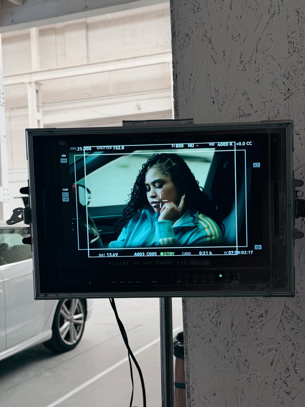 A director's monitor on set showing a woman in a car during a shoot